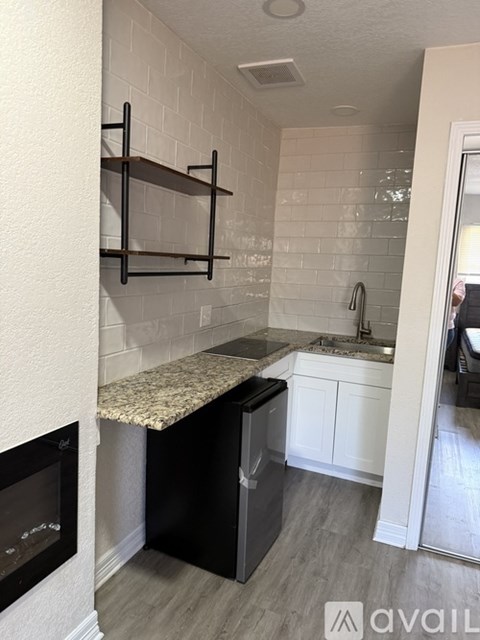A kitchen with a black dishwasher and a granite countertop.