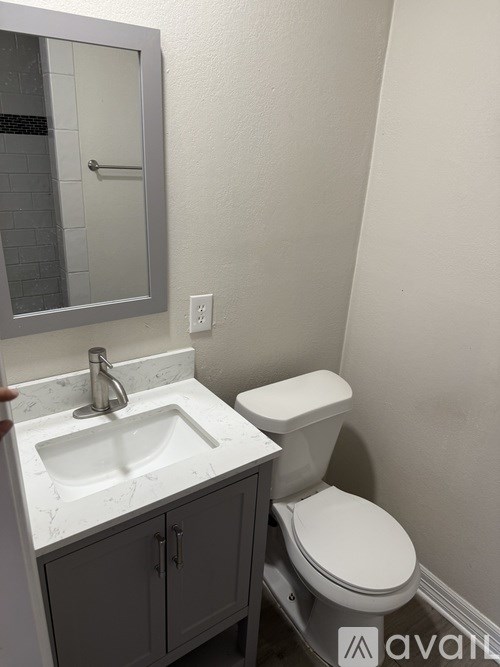 A bathroom with a toilet, sink and mirror.