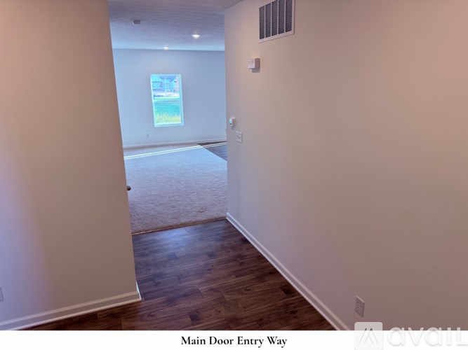 A room with wooden floors and a window showing a view of a building and some greenery.