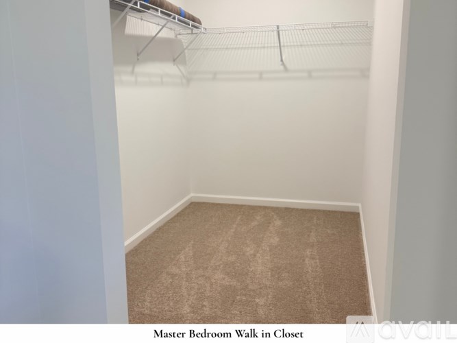 A room with a carpeted floor and a window showing a view of a house across the street.