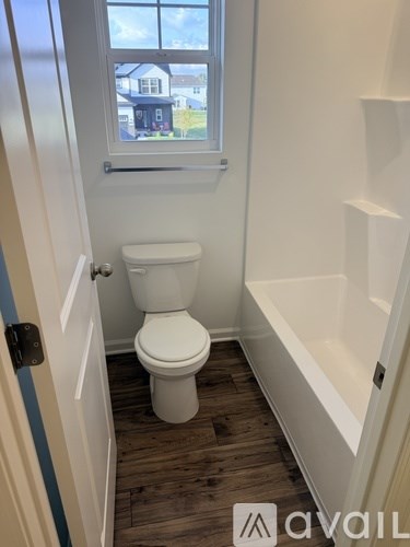 A white toilet in a small bathroom with a window.