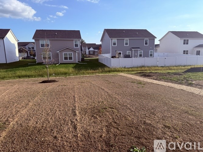 A dirt field with a row of houses in the background.