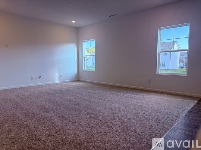 A room with a carpeted floor and two windows.
