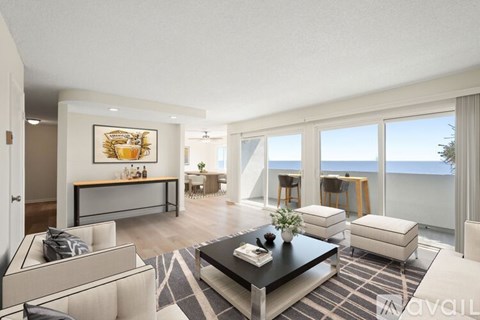 A living room with a couch, coffee table, and a painting of a fruit bowl on the wall.