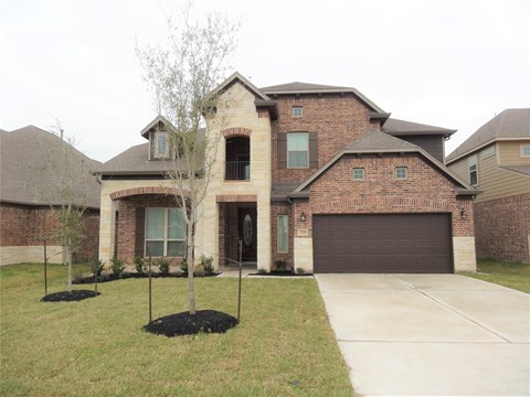 A large house with a garage and a tree in front.
