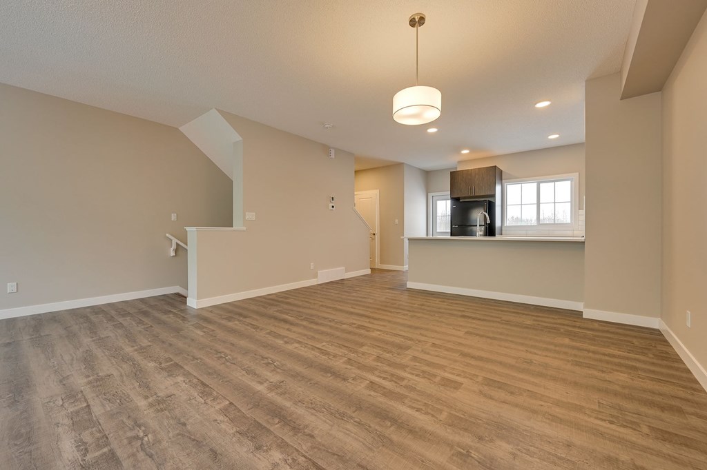 A spacious room with wooden flooring and a large window.