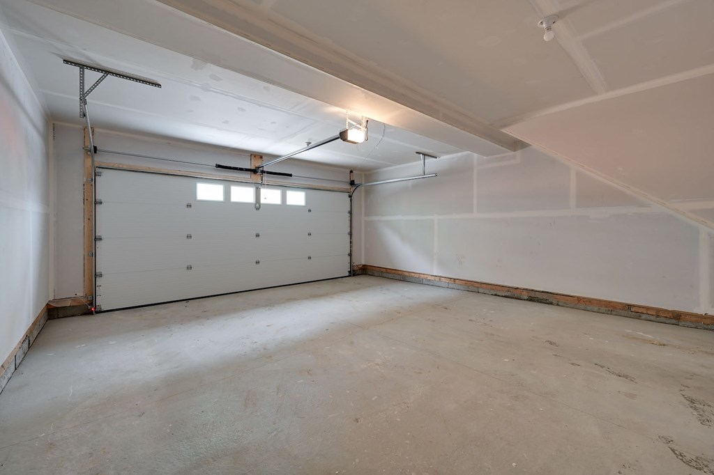 A large empty room with a white door and a window.