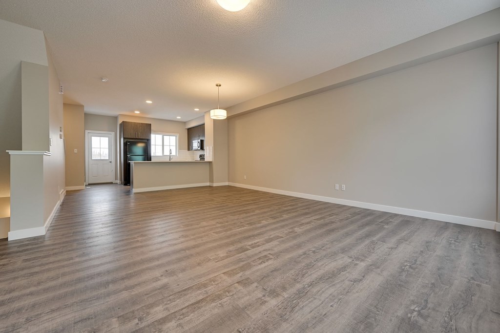 A spacious room with wooden flooring and a large window.