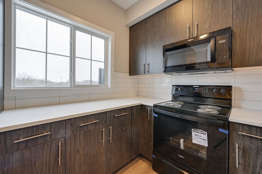 A kitchen with a black oven and microwave above it.