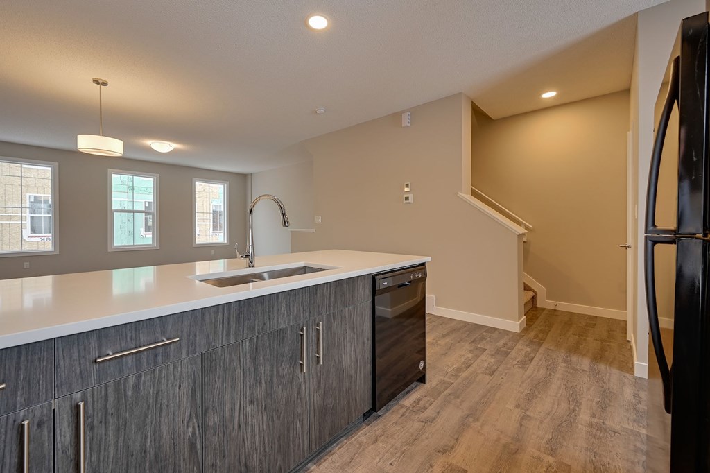 A kitchen with a sink, cabinets, and a refrigerator.
