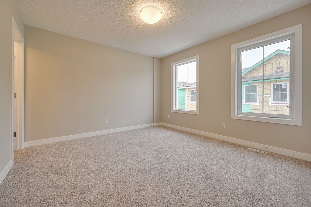 A room with a carpeted floor and two windows.