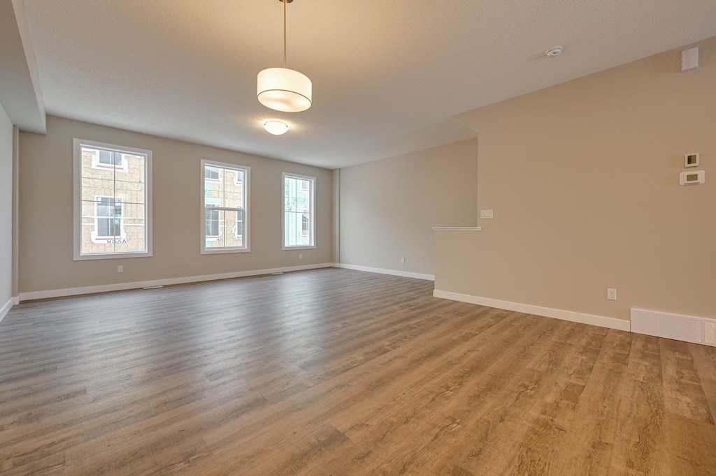 A large empty room with wooden floors and three windows.