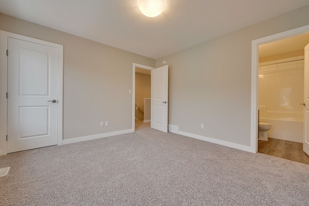 A room with a carpeted floor and a door on the left side.