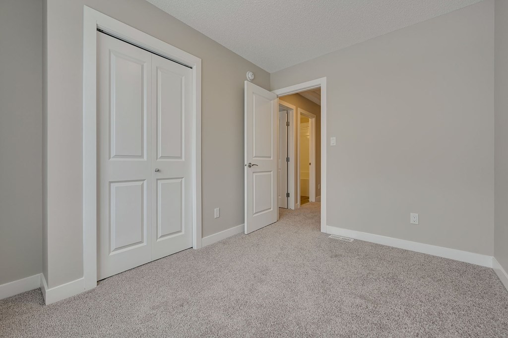 A room with a carpeted floor and two doors.