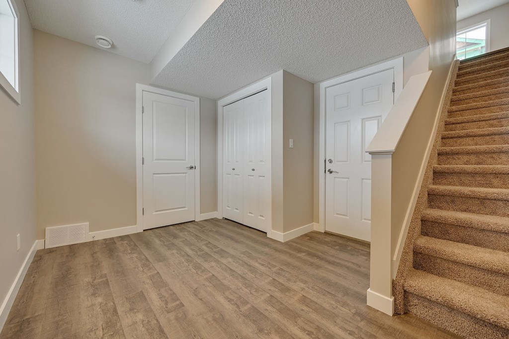 A staircase with a beige carpeted runner leads up to a white door.