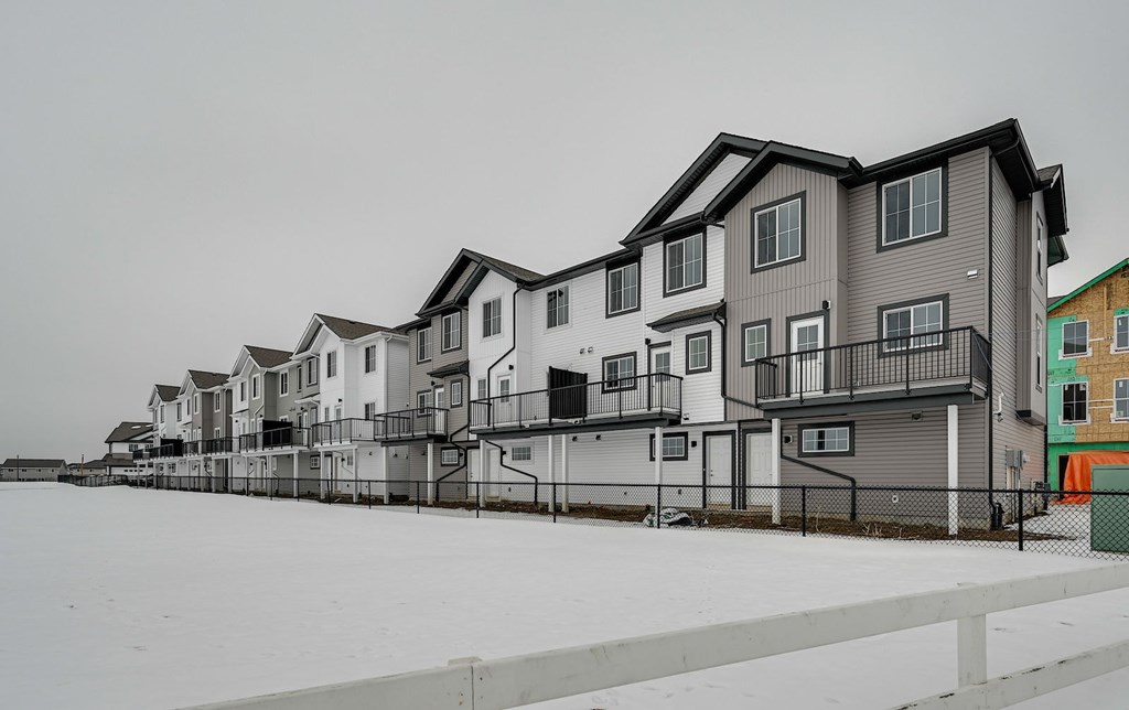 A row of houses with a snowy ground in front.