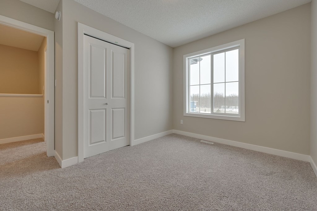 A room with a white door and a window with a view of trees outside.