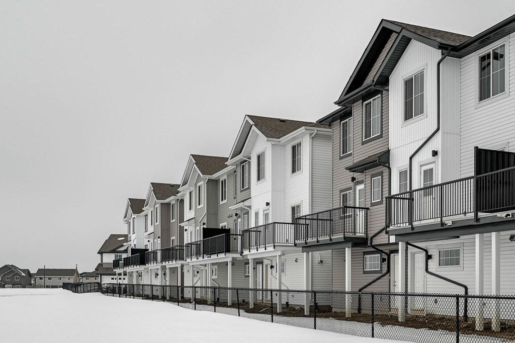 A row of houses with balconies and fences in front.