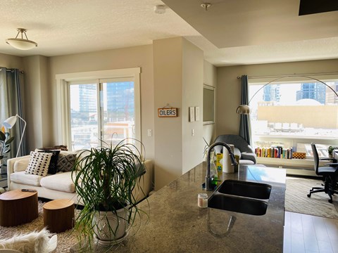 A living room with a couch, a chair, and a kitchen area with a sink.