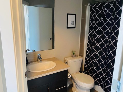 A bathroom with a white toilet, sink, and black and white shower curtain.