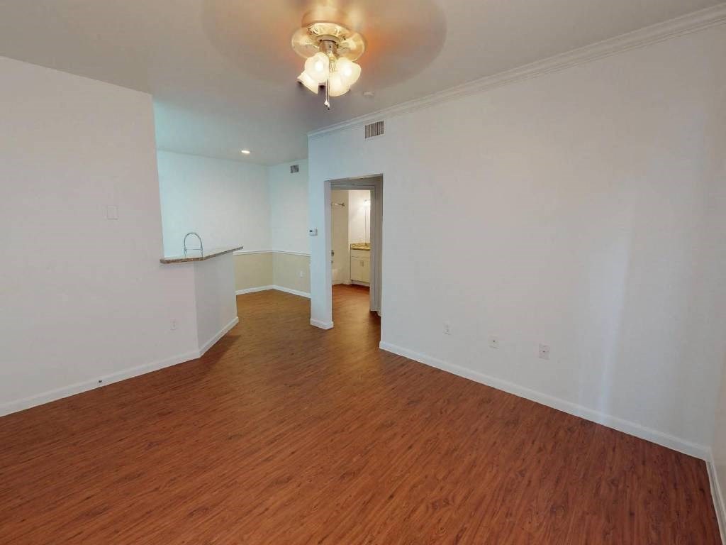 A room with wooden floors and a white ceiling with a chandelier.