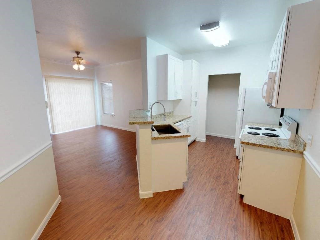 A kitchen with white cabinets and a wooden floor.