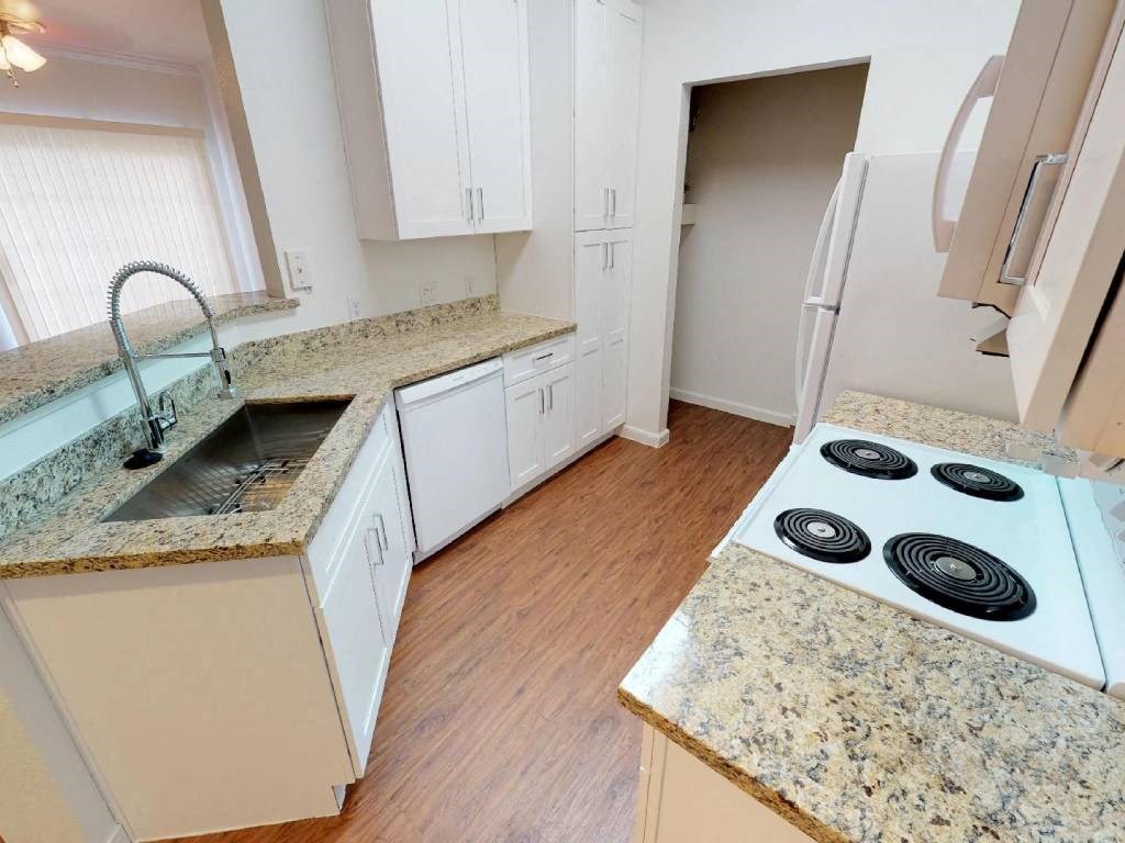 A kitchen with granite countertops and white cabinets.