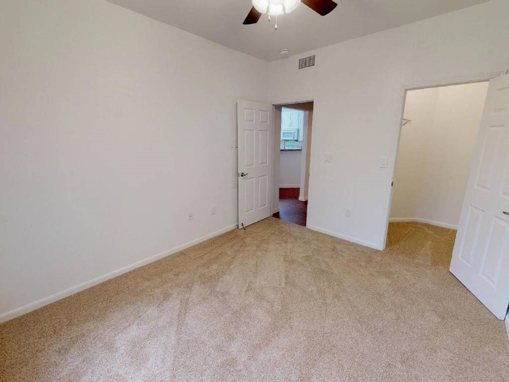 A room with a carpeted floor and a ceiling fan.