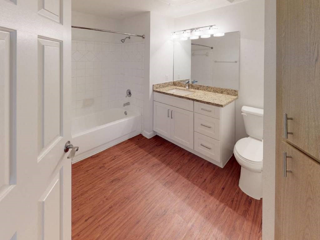 A bathroom with a wooden floor and white walls.