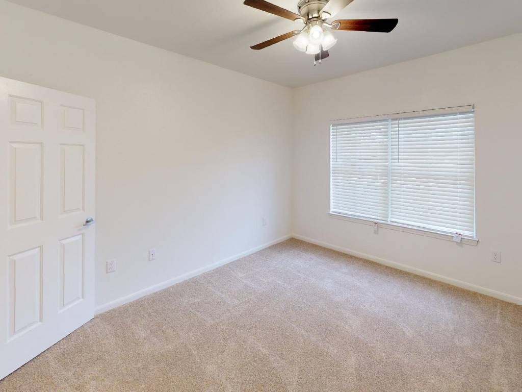 A room with a ceiling fan and a window with blinds.