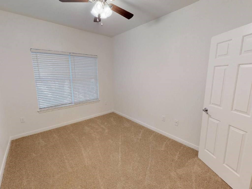 A room with a ceiling fan and a window with blinds.