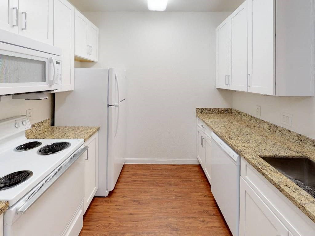 A kitchen with white appliances and cabinets.