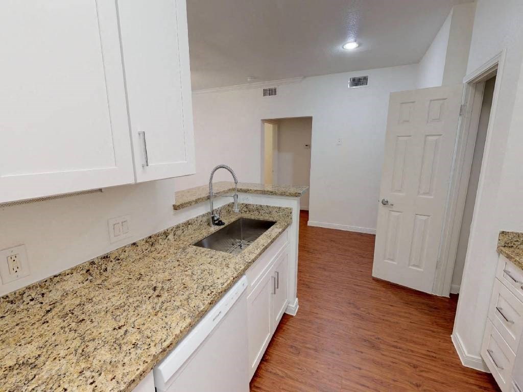A kitchen with granite countertops and white cabinets.