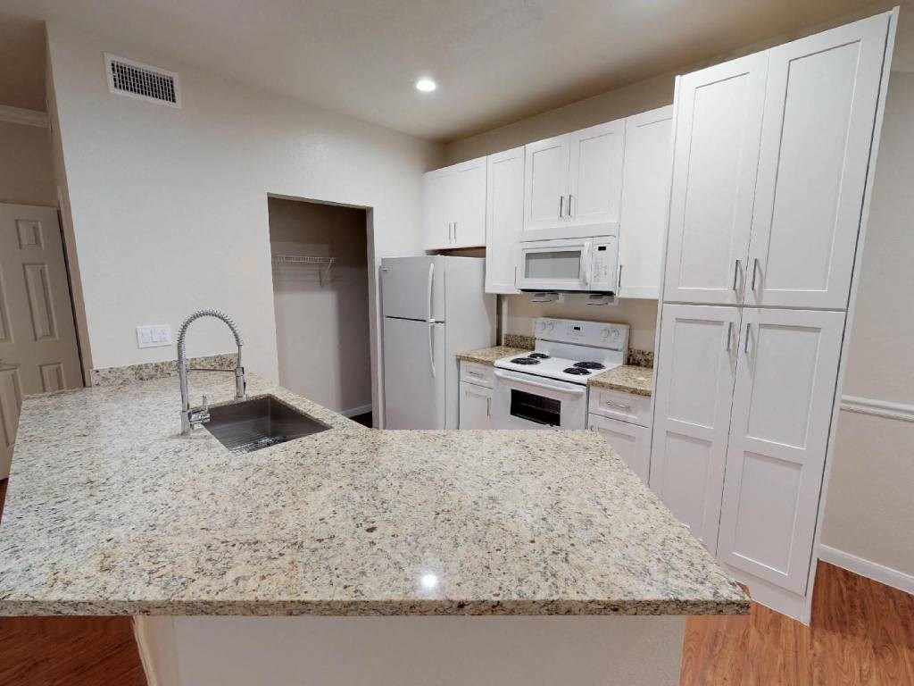 A kitchen with granite countertops and white cabinets.