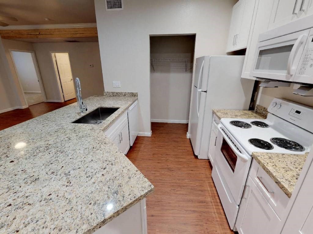 A kitchen with granite countertops and white appliances.