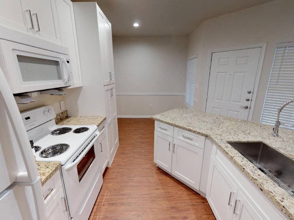 A kitchen with white cabinets and a granite countertop.