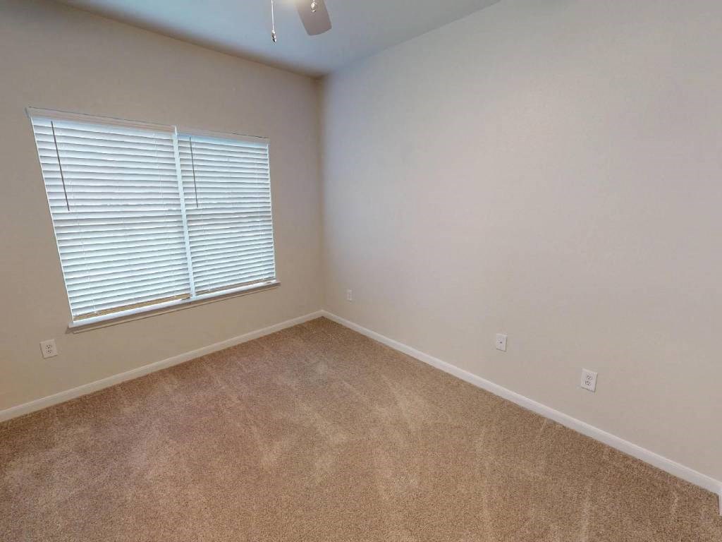 A room with a carpeted floor and a window with blinds.