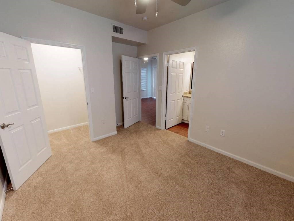 A room with white walls and carpeted floor with a door on the left.
