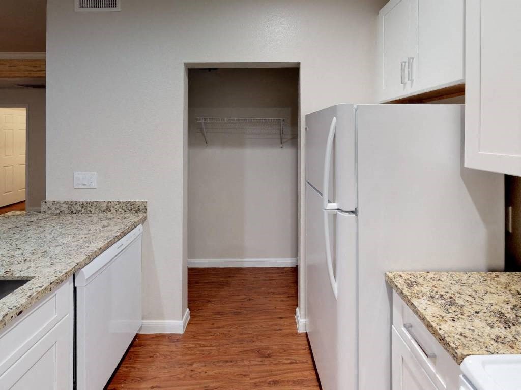 A kitchen with a white fridge and cabinets.