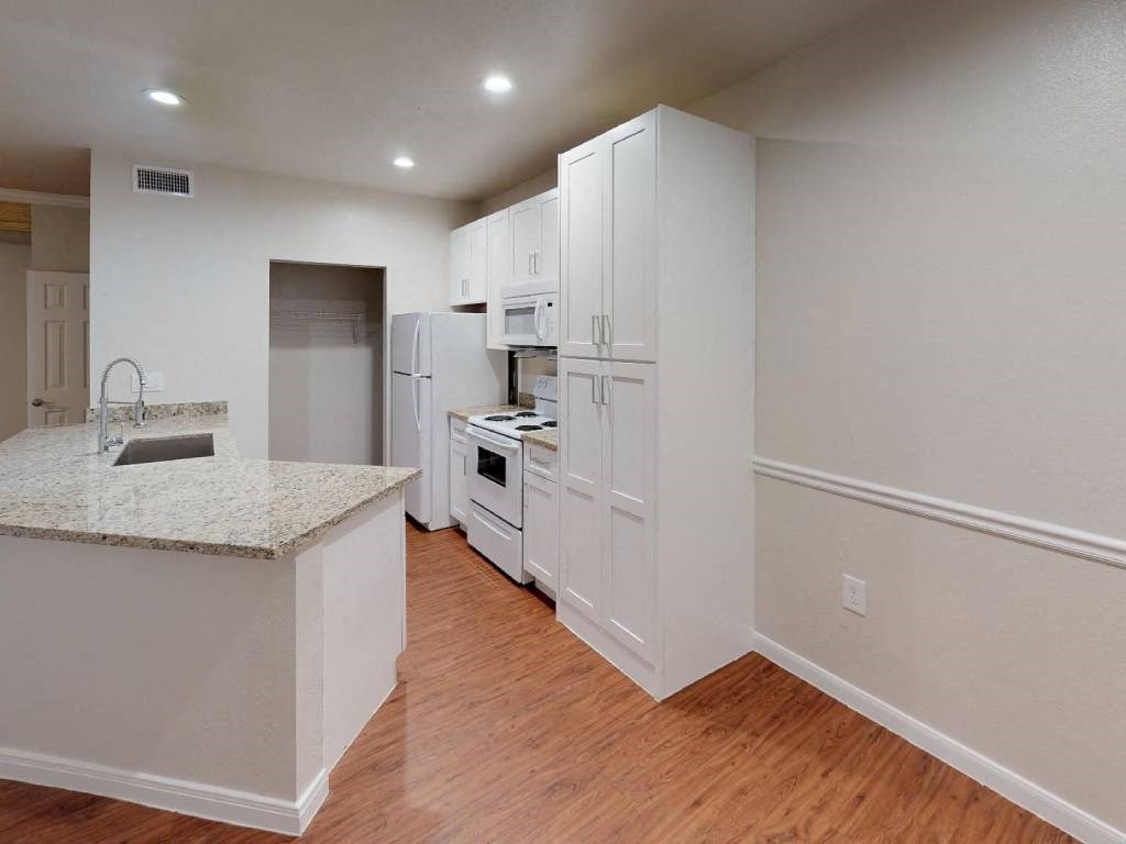 A kitchen with white cabinets and a granite countertop.