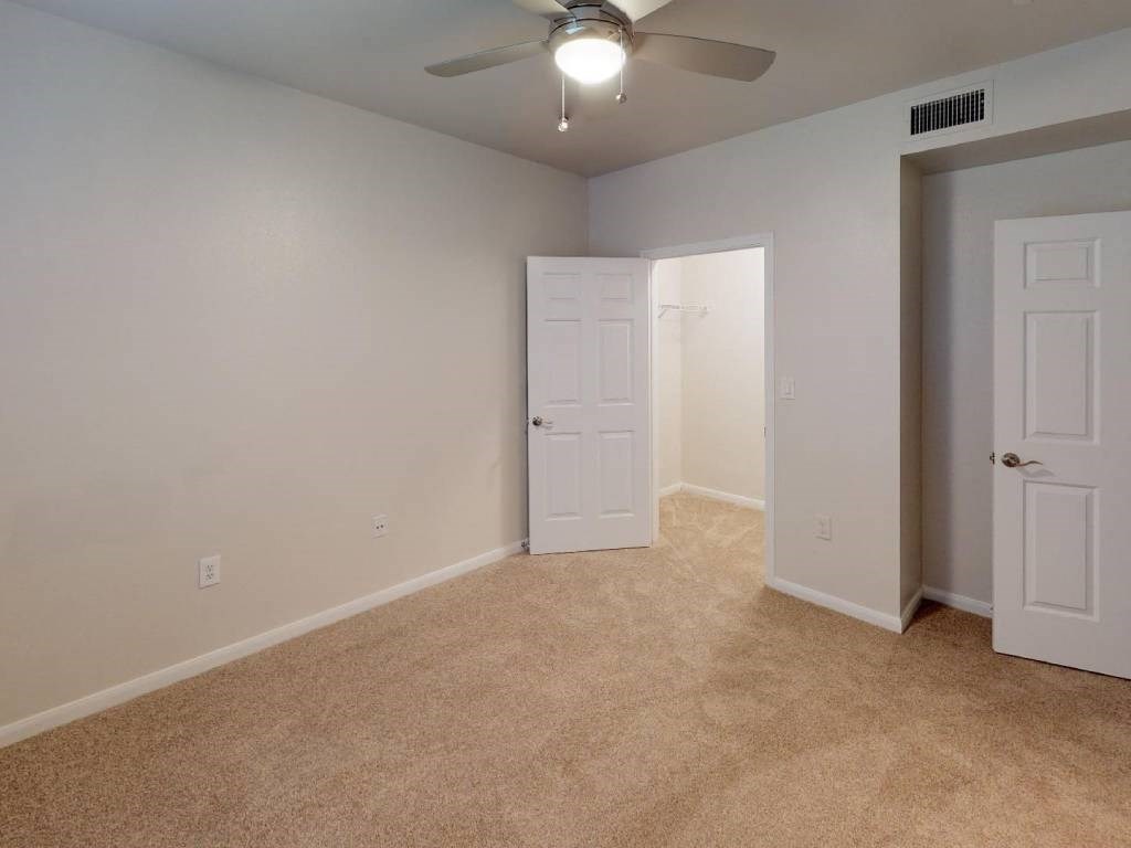 A room with a ceiling fan and two doors.