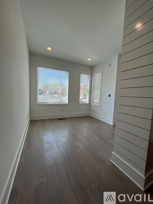 A room with wooden flooring and a window with blinds.