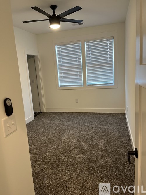 A room with a ceiling fan and carpeted floor.