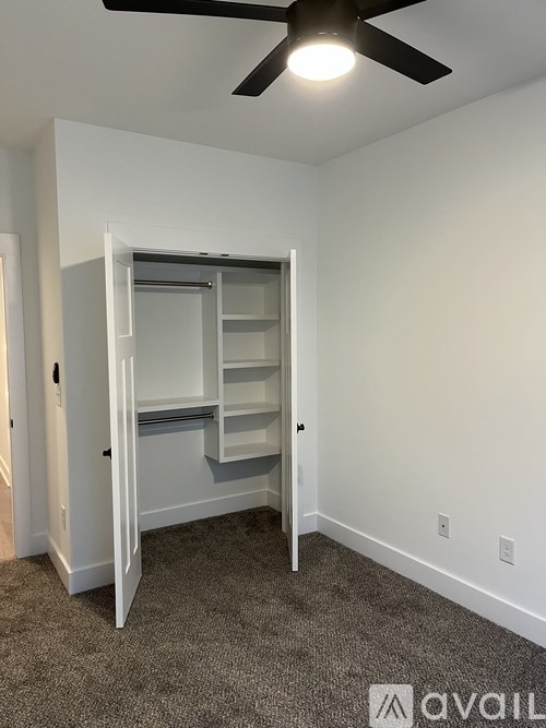 A room with a white wall and a ceiling fan.
