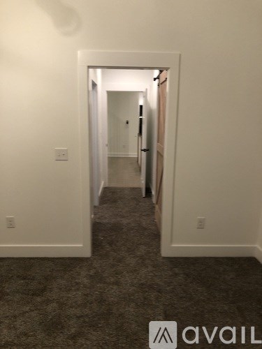 A hallway with a carpeted floor and white walls.