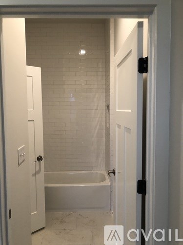 A bathroom with a white tub and tiled walls.