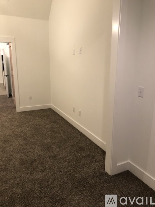 A hallway with carpeted flooring and white walls.