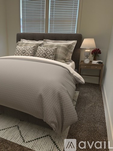 A bedroom with a large bed and a nightstand with a lamp.