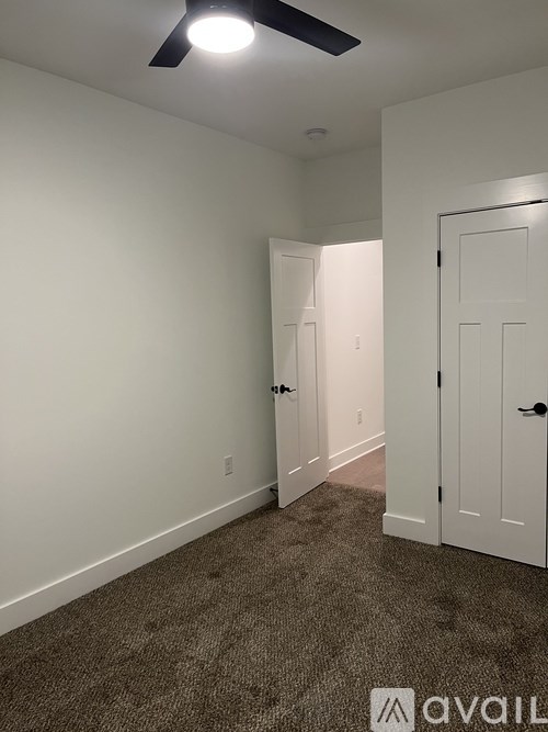 A room with a carpeted floor and two doors.