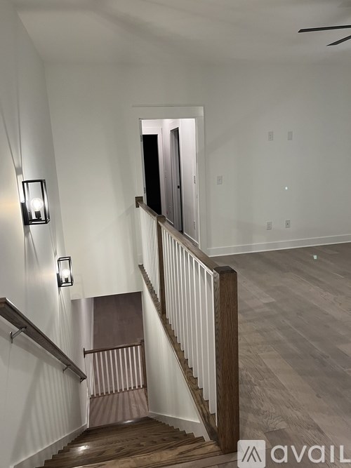 A staircase with a wooden handrail and a light on the wall.
